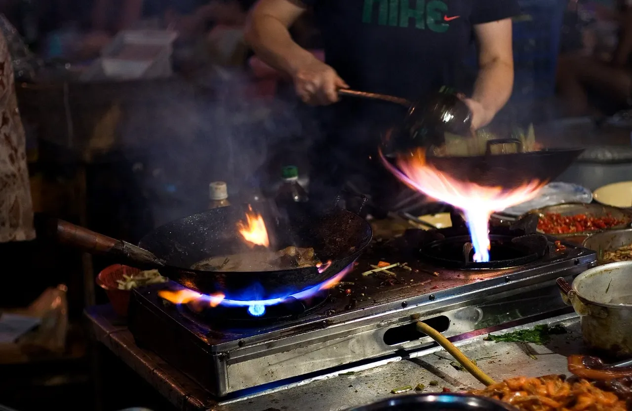 Wok en fonte à feu vif dans la cuisine du restaurant BASHU à Paris